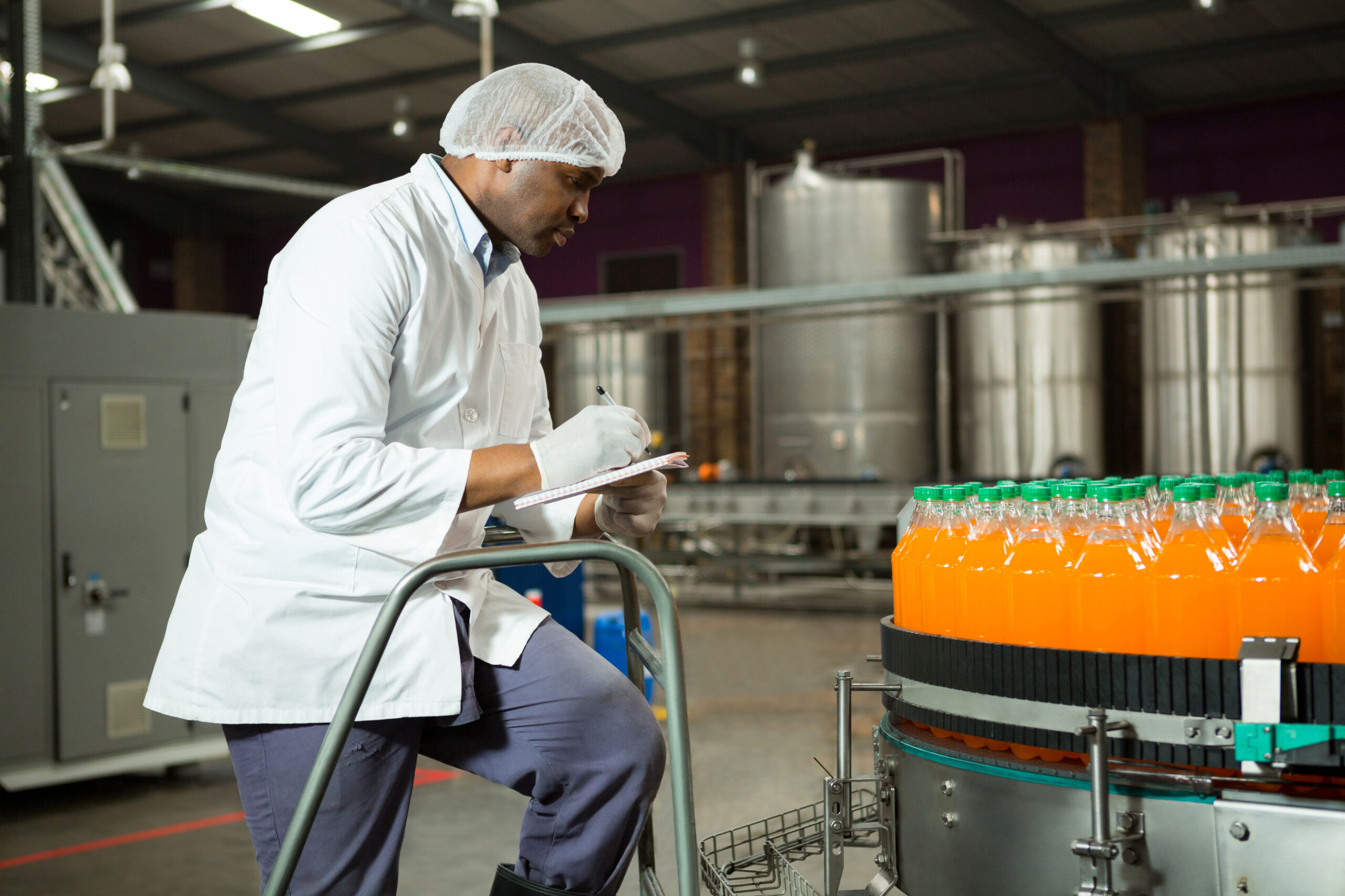 Male worker checking bottles in juice factory
